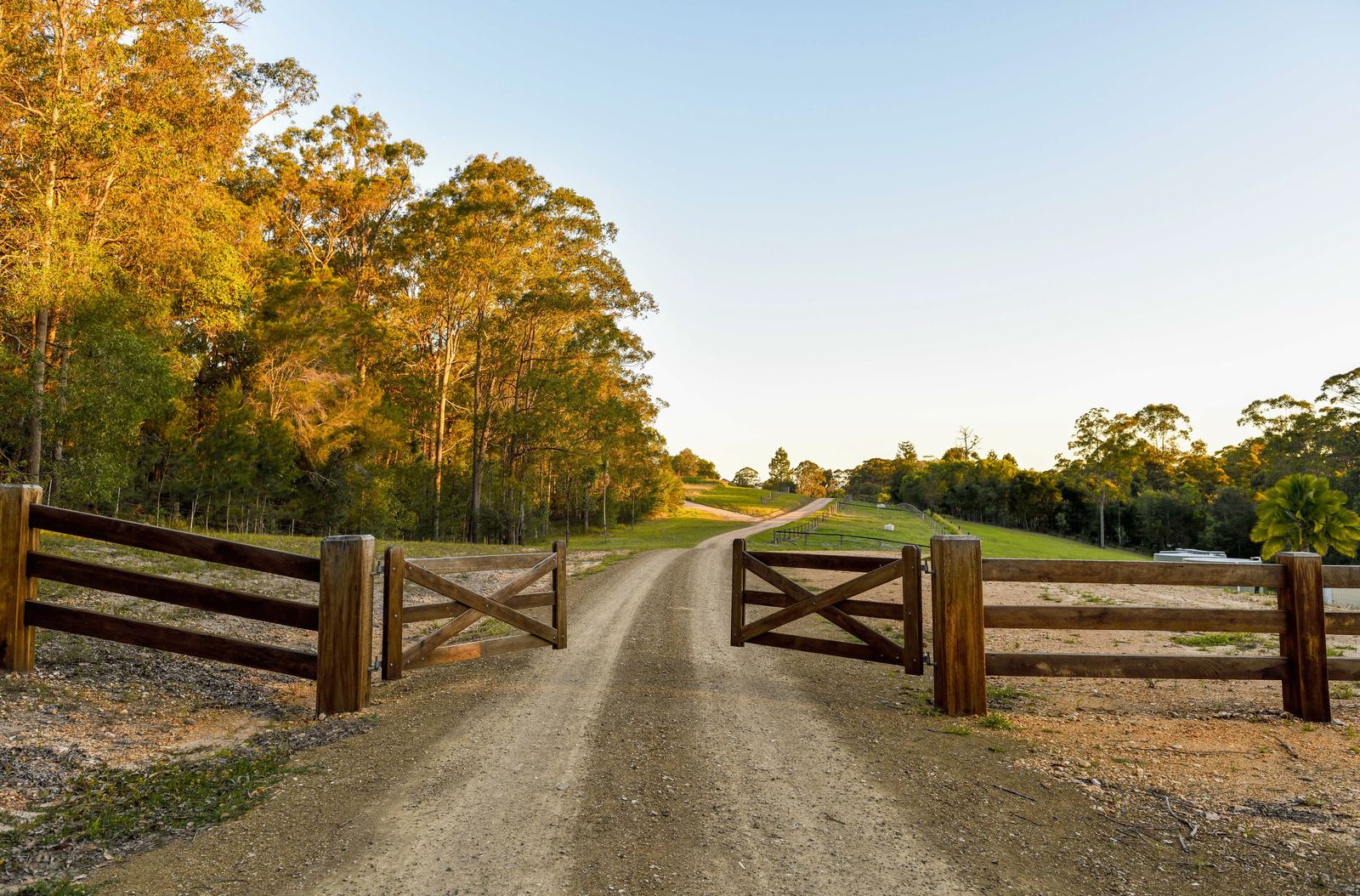 Timber farm gates standing open across a gravel drive at La Boscosa Estate